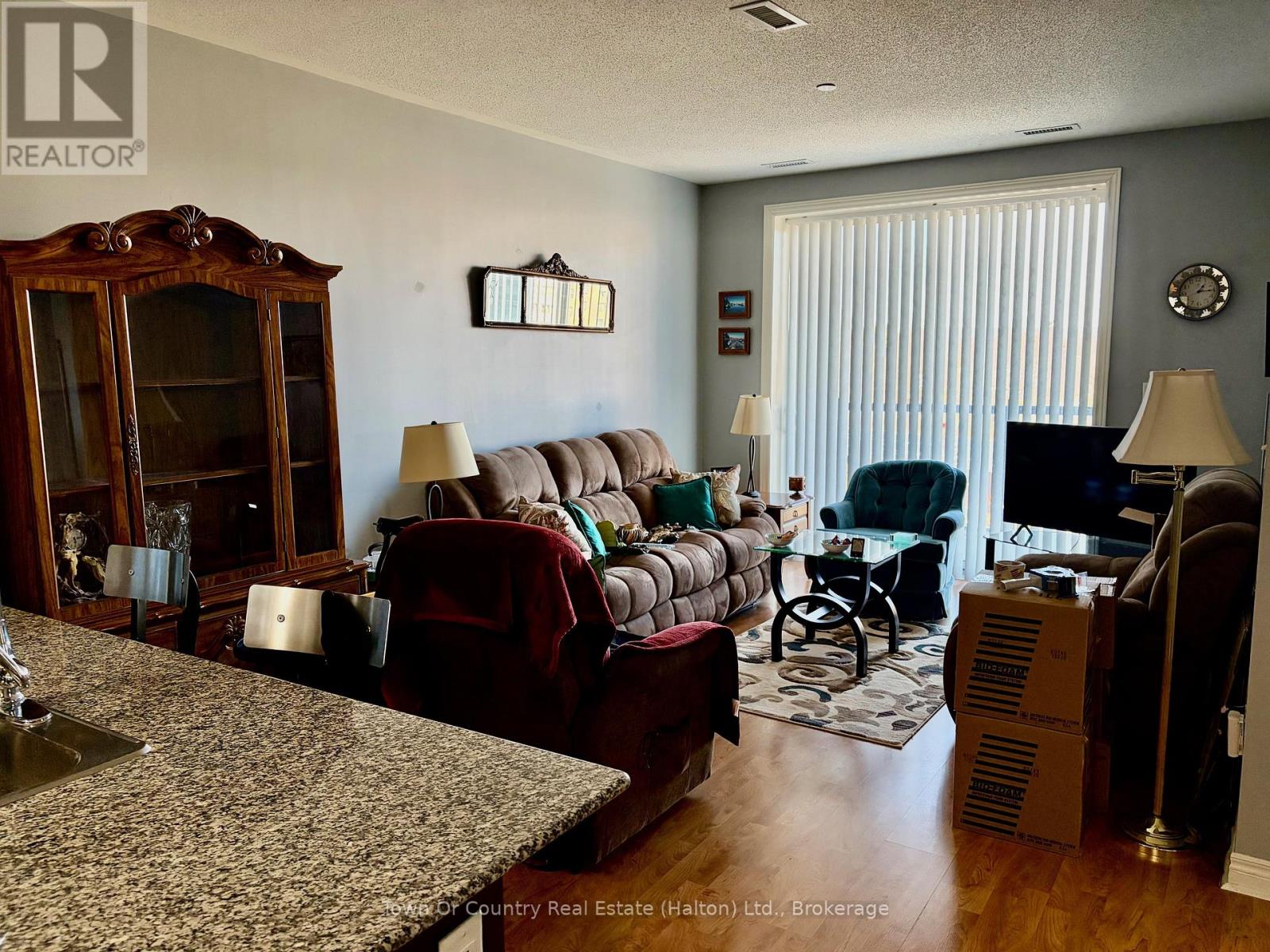 A living room with a wooden cabinet, a sofa, a chair, a table, and a TV.