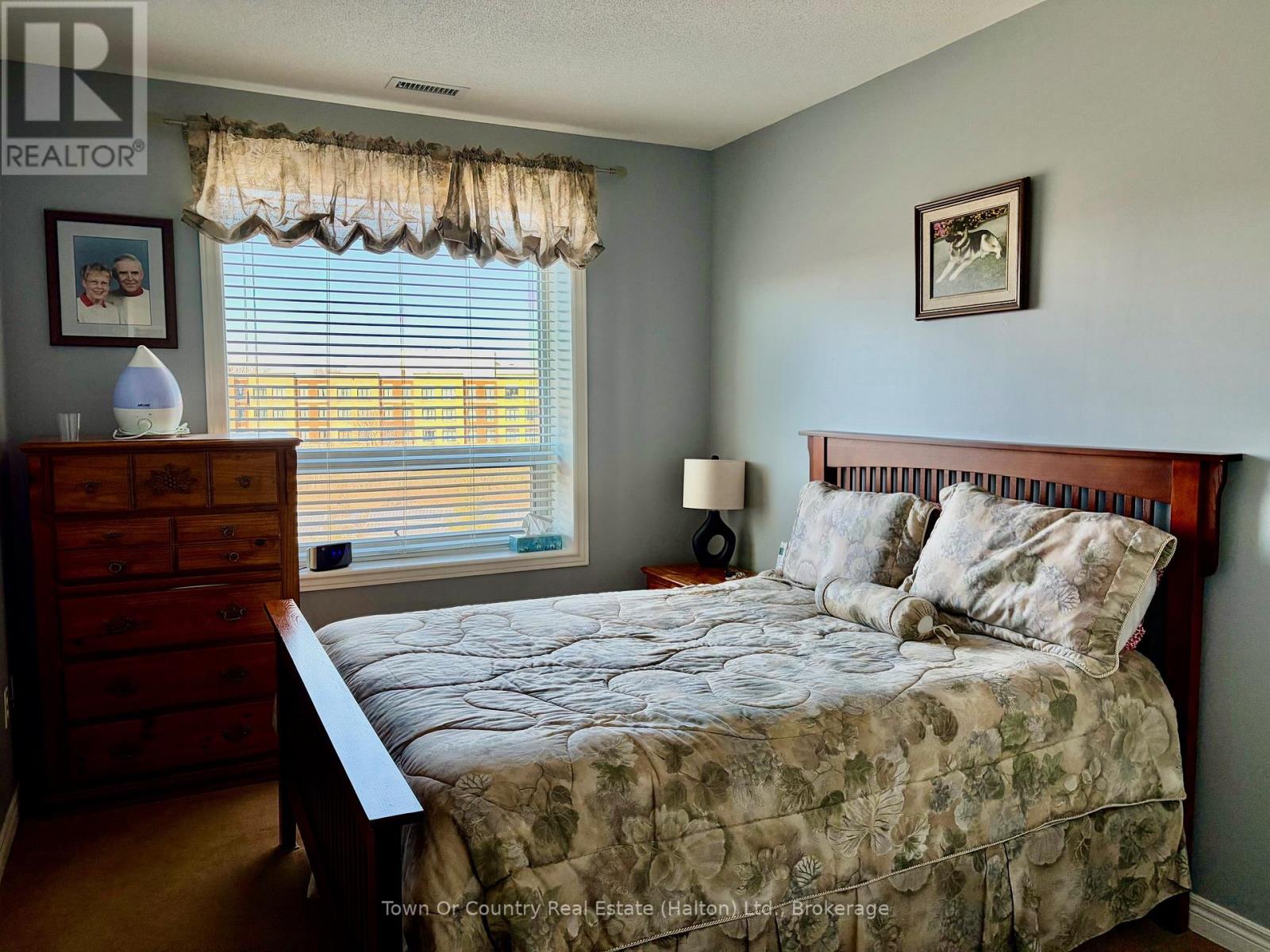 A bedroom with a bed, dresser, and window with blinds.
