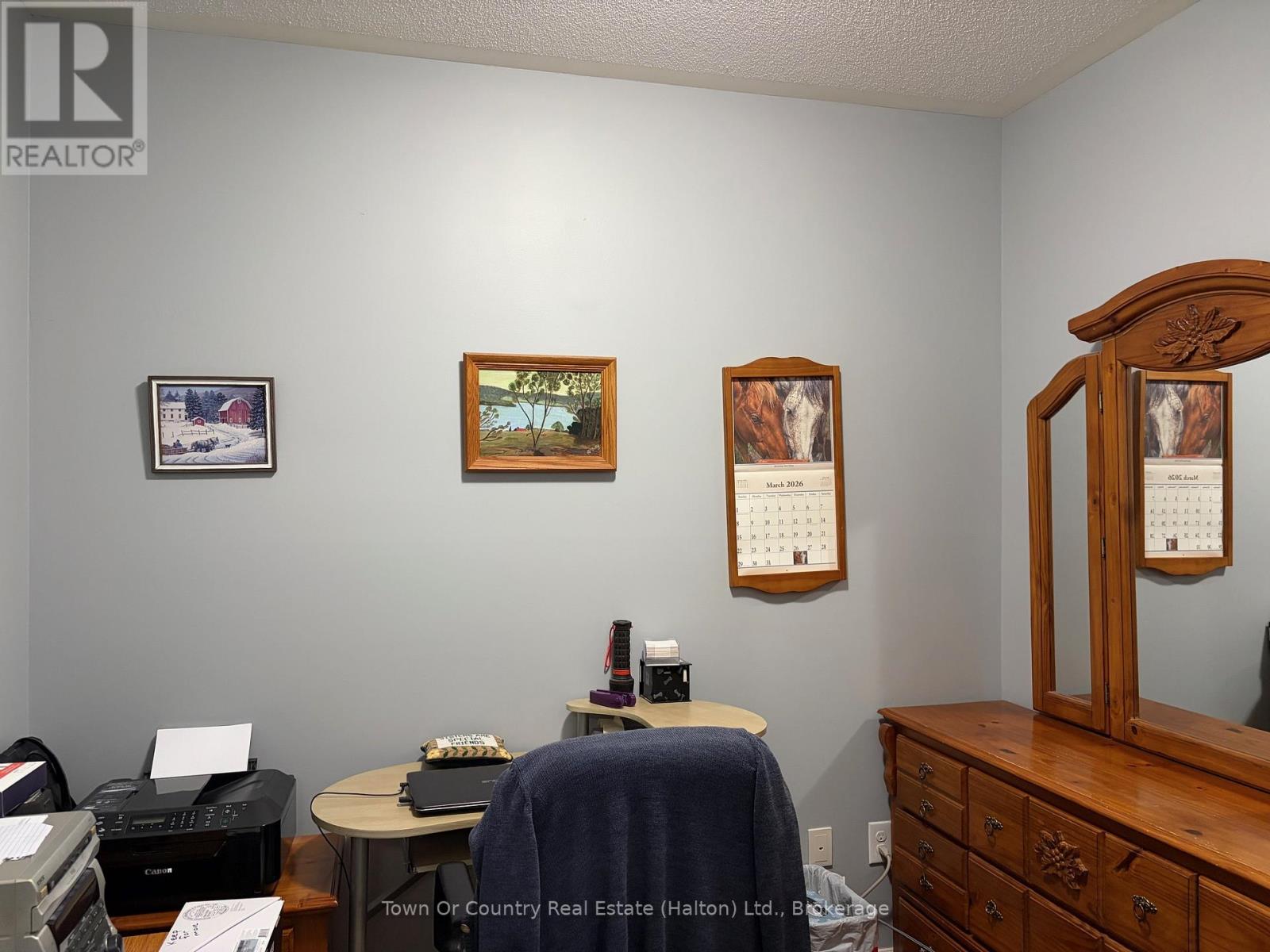 A realtor's office with a desk, chair, and pictures on the wall.