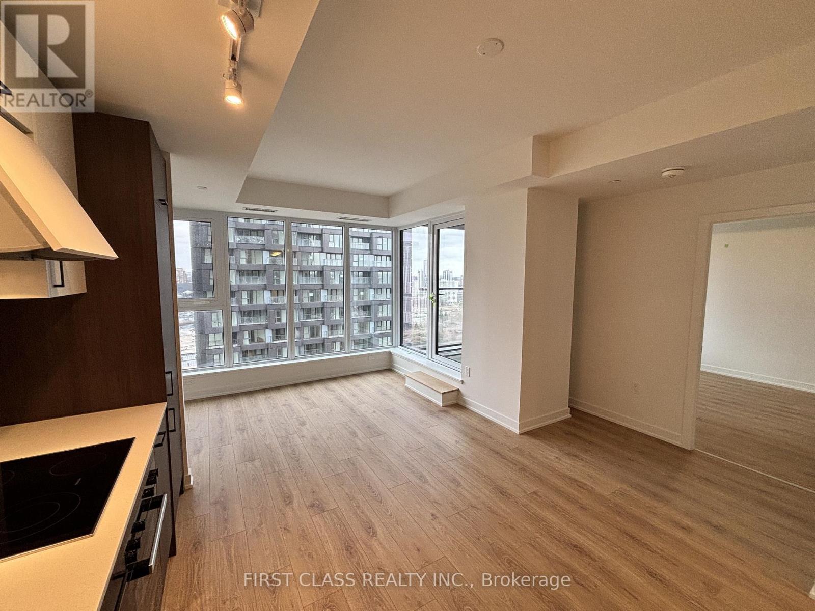 A spacious room with wooden flooring and a large window overlooking a cityscape.