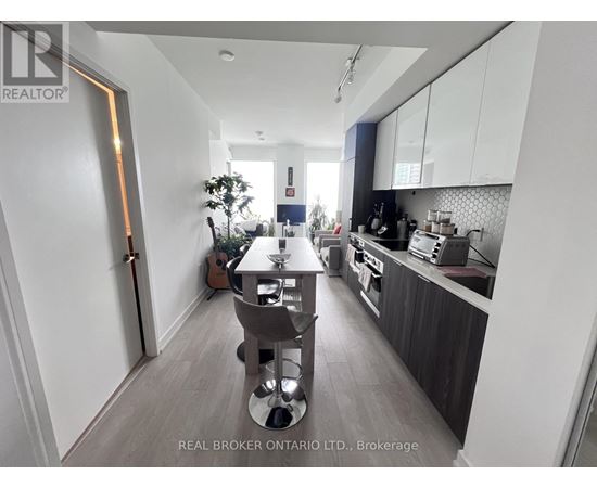 A well-lit kitchen with a dining table and chairs in the middle.