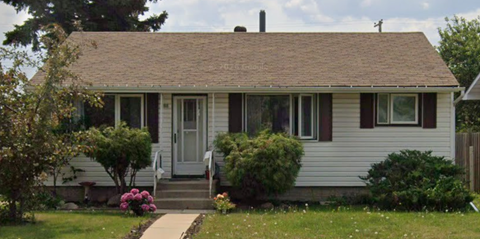 A small white house with a brown door and a small porch.