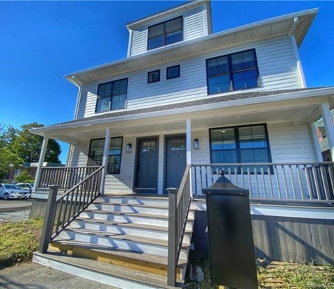 A two-story house with a front porch and stairs leading up to the entrance.