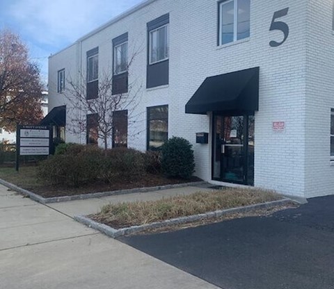 A white building with a black awning and a sign that reads "5" on the front.