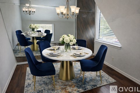 A dining room with a round table and blue chairs.
