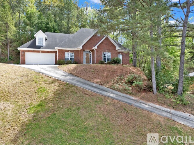 A house with a garage is surrounded by trees.