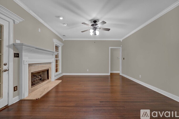 A spacious room with a fireplace and a ceiling fan.