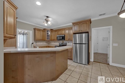 A kitchen with wooden cabinets and a stainless steel refrigerator.