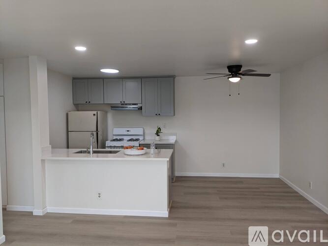 A kitchen with white cabinets and a white fridge is available.
