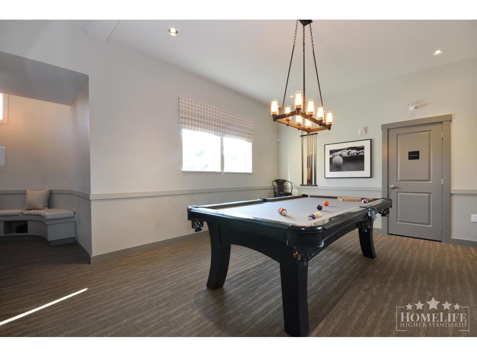 A pool table is in the middle of a room with a bench and a picture on the wall.