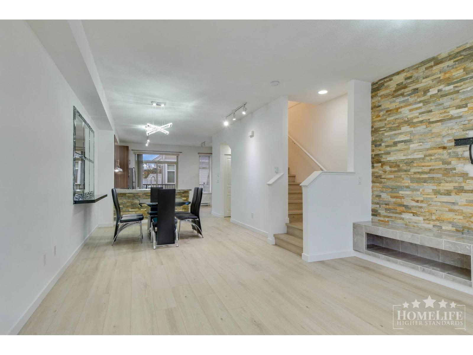 A spacious living room with a stone wall and a staircase.