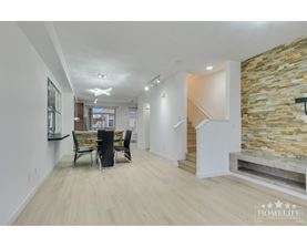 A spacious living room with a stone wall and a staircase.