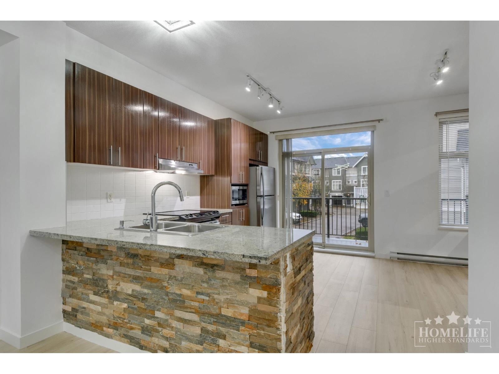 A kitchen with a stone counter and wooden cabinets.