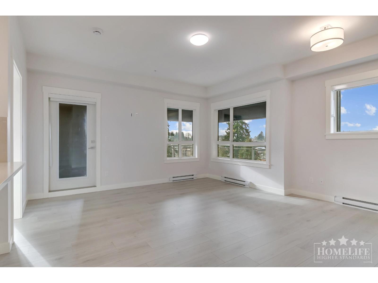 A spacious room with a large window and a door leading to another room.