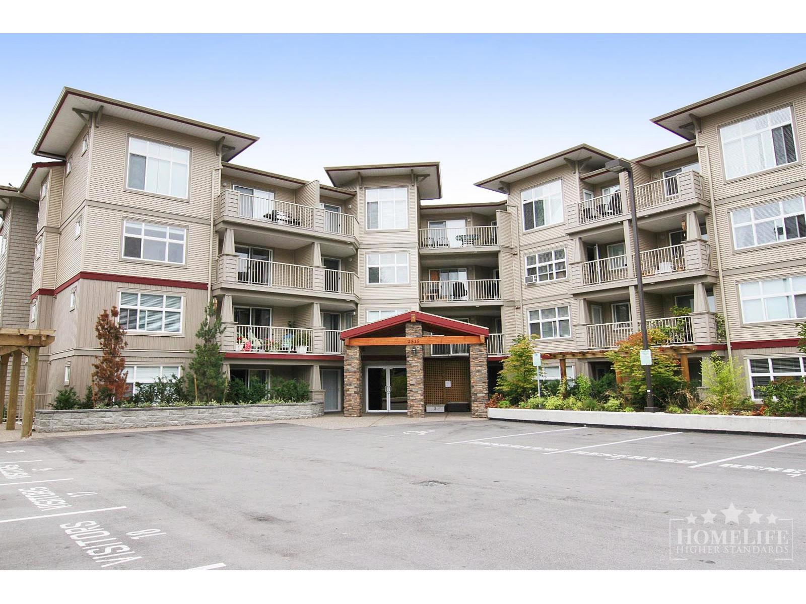 A large apartment complex with a parking lot in front.