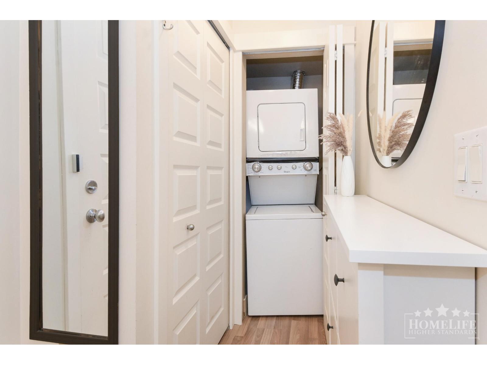 A small white kitchen with a dishwasher and a fridge.