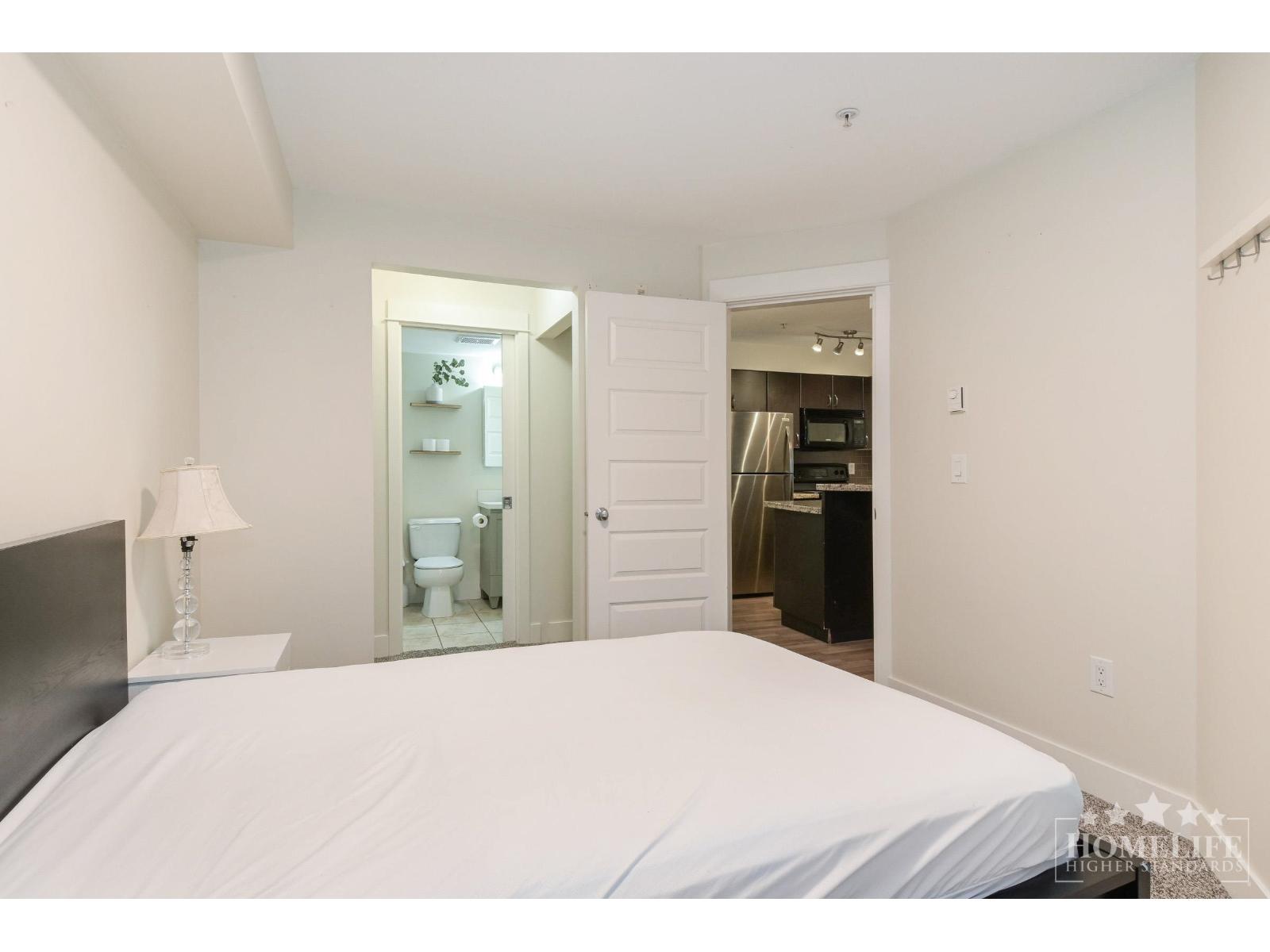 A white bedroom with a large bed and a mirror on the wall.