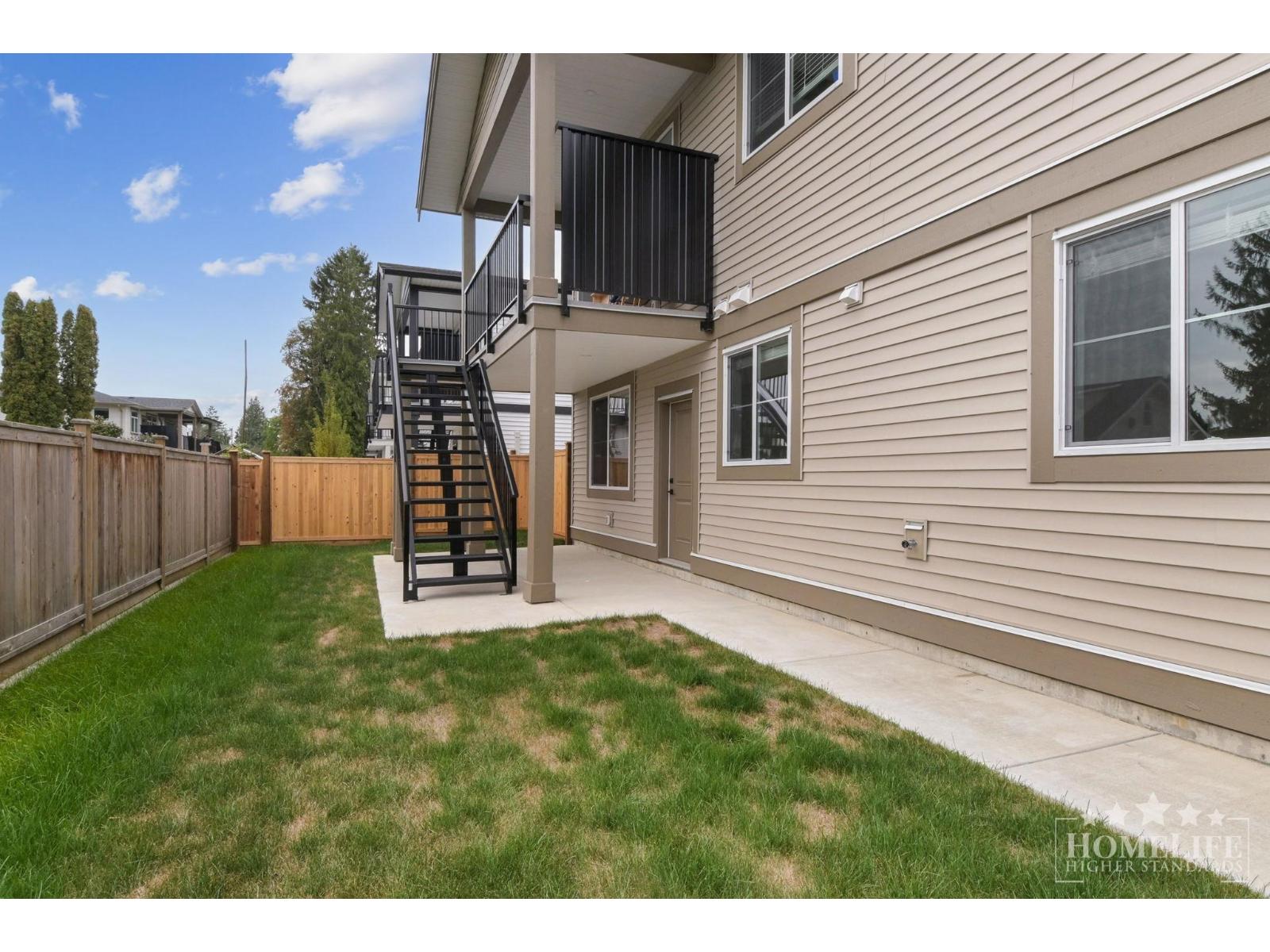 A house with a small backyard and a metal staircase.