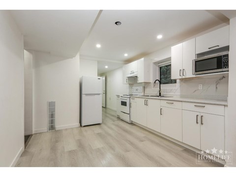 A kitchen with white cabinets and appliances in a white room.