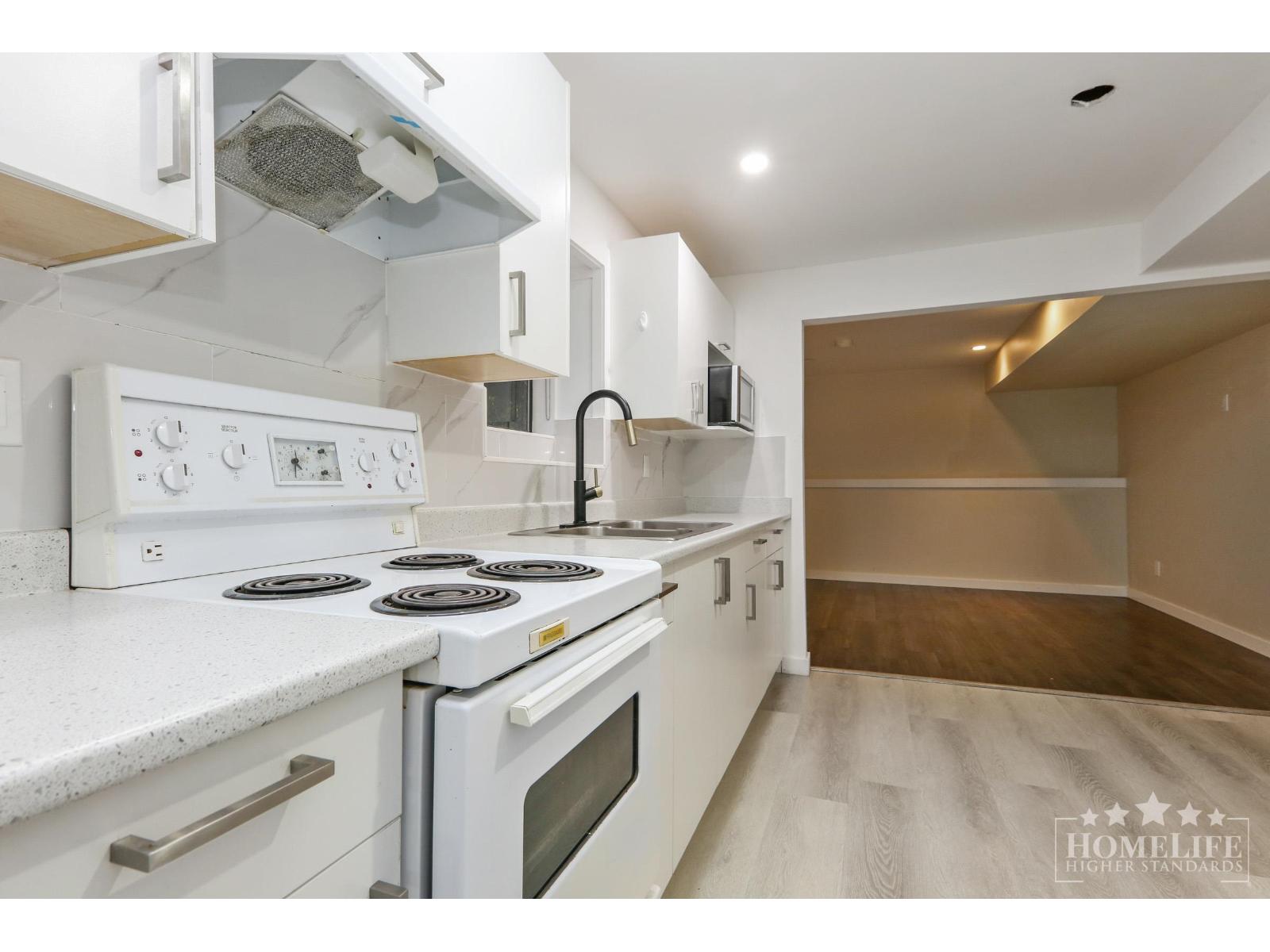 A white kitchen with a stove top oven and a microwave.