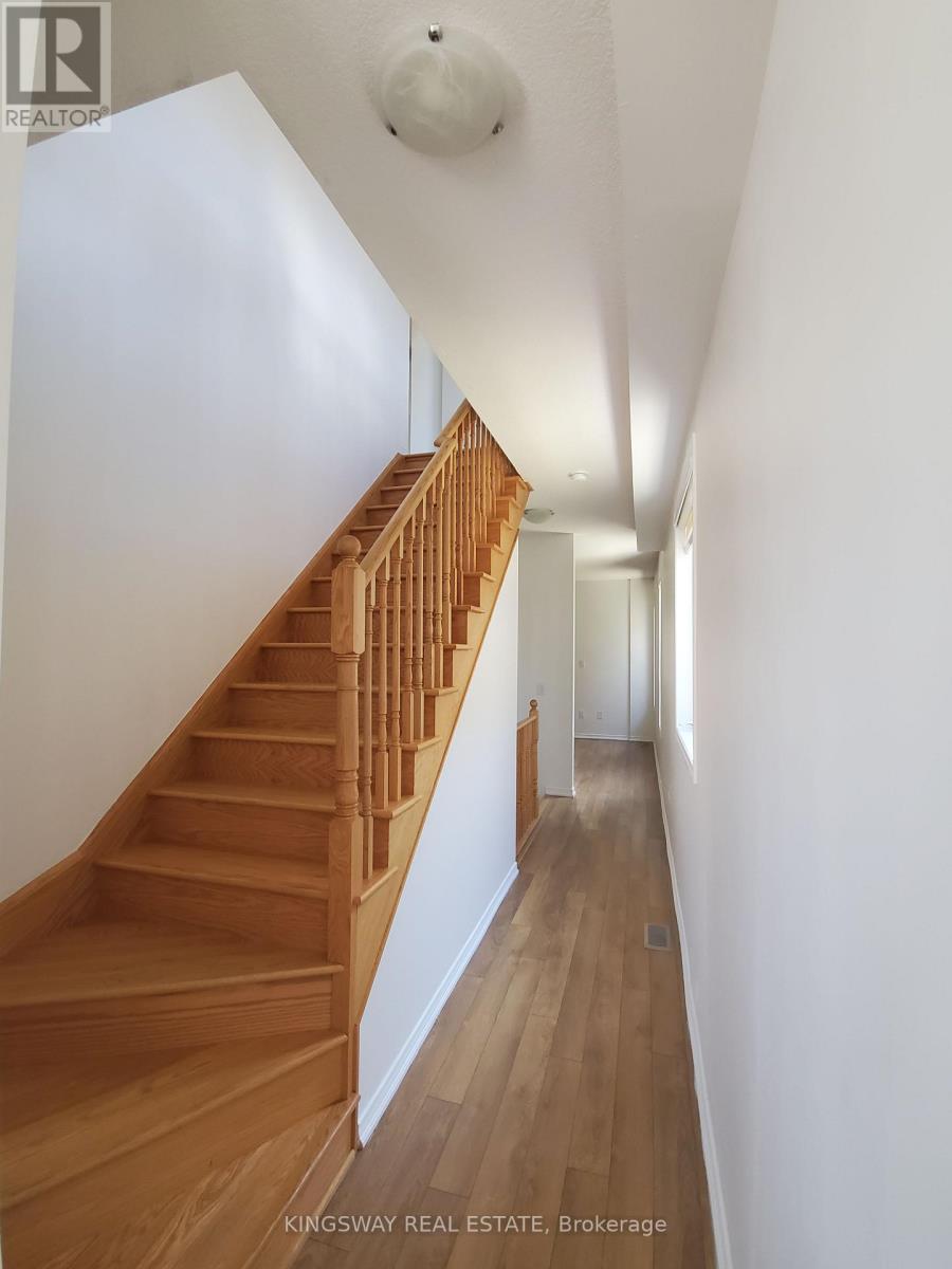A wooden staircase in a white hallway.