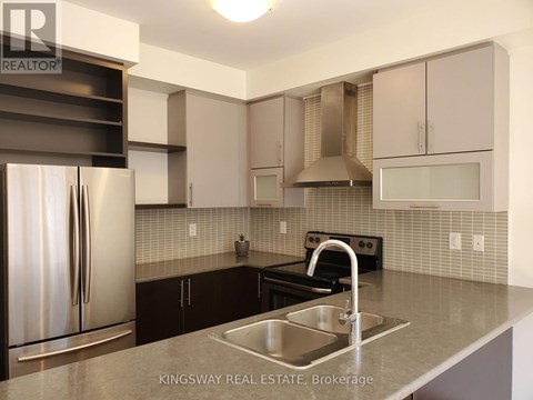 A kitchen with a stainless steel refrigerator and a sink.