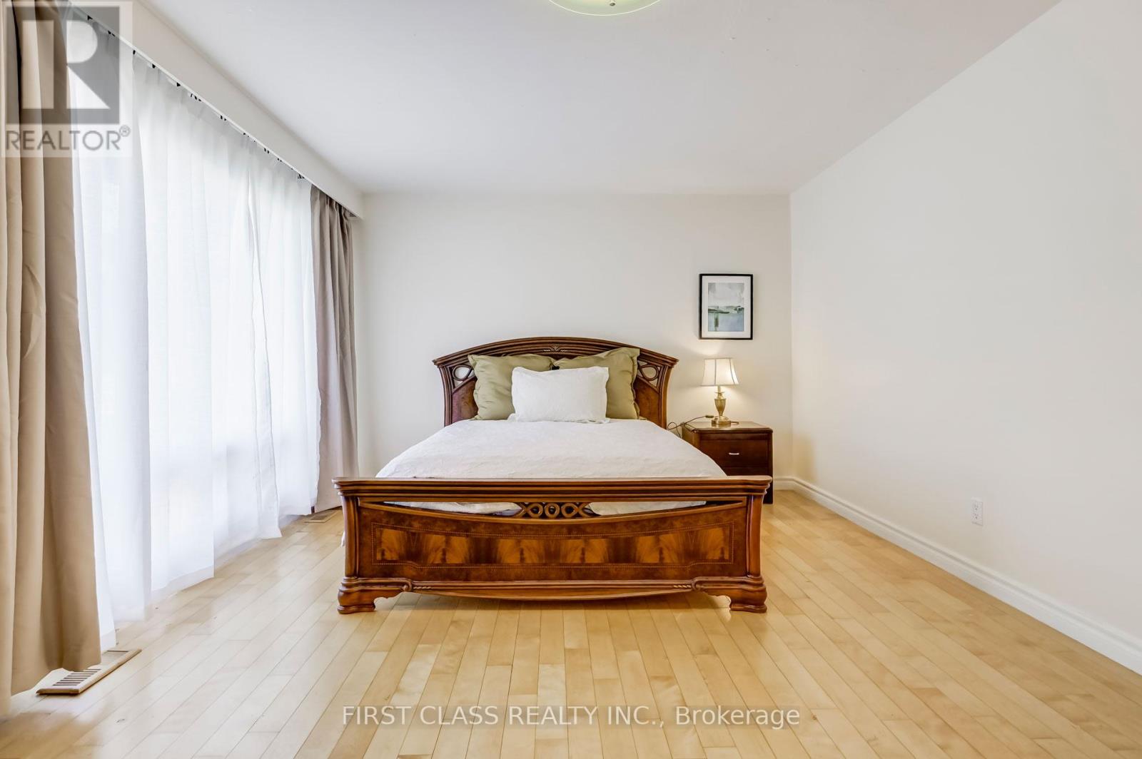 A bedroom with a large bed and wooden floors.