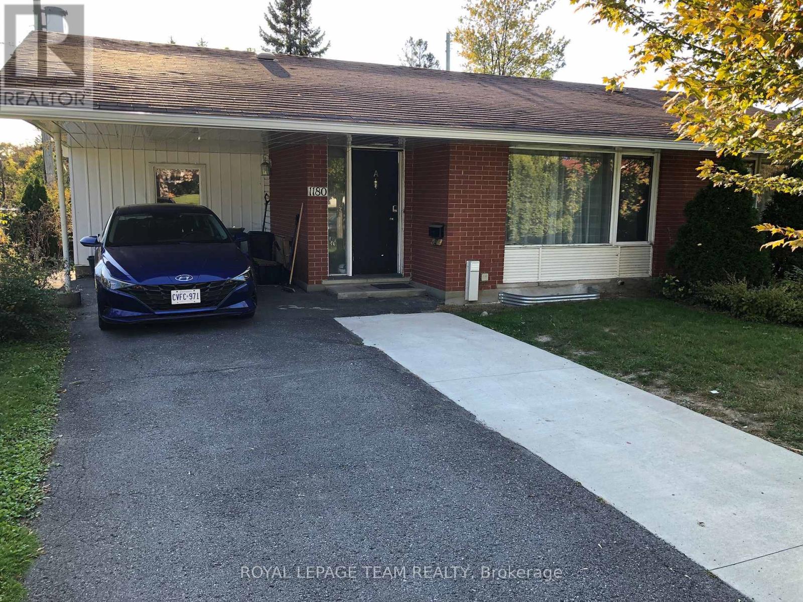 A blue car is parked in front of a house with a white garage door.