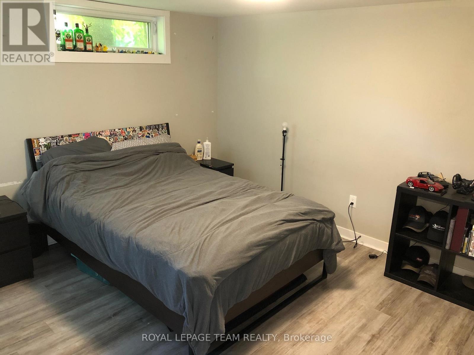 A bedroom with a bed, nightstand, and a shelf with shoes.