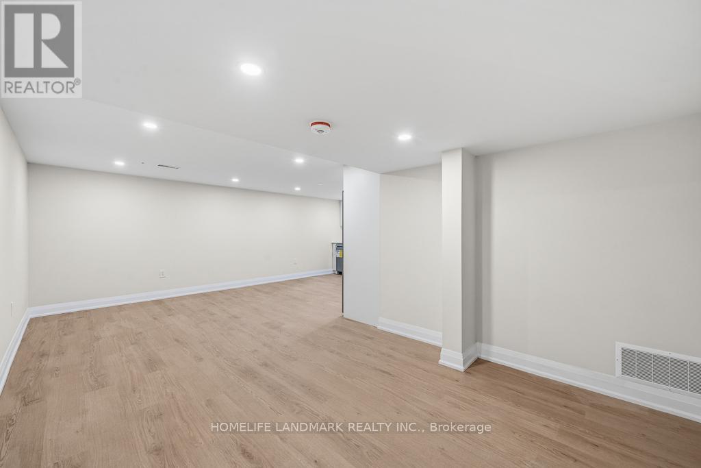 A spacious room with wooden flooring and white walls, with a logo in the top left corner.