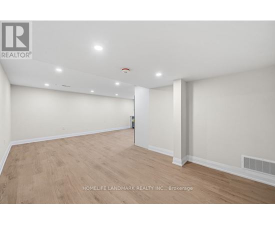 A spacious room with wooden flooring and white walls, with a logo in the top left corner.