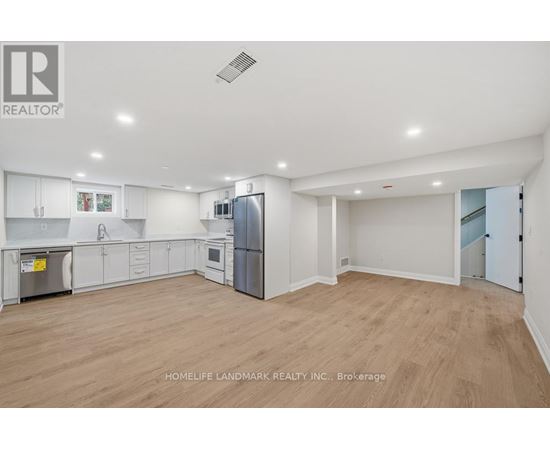 A spacious kitchen with white cabinets and a refrigerator.