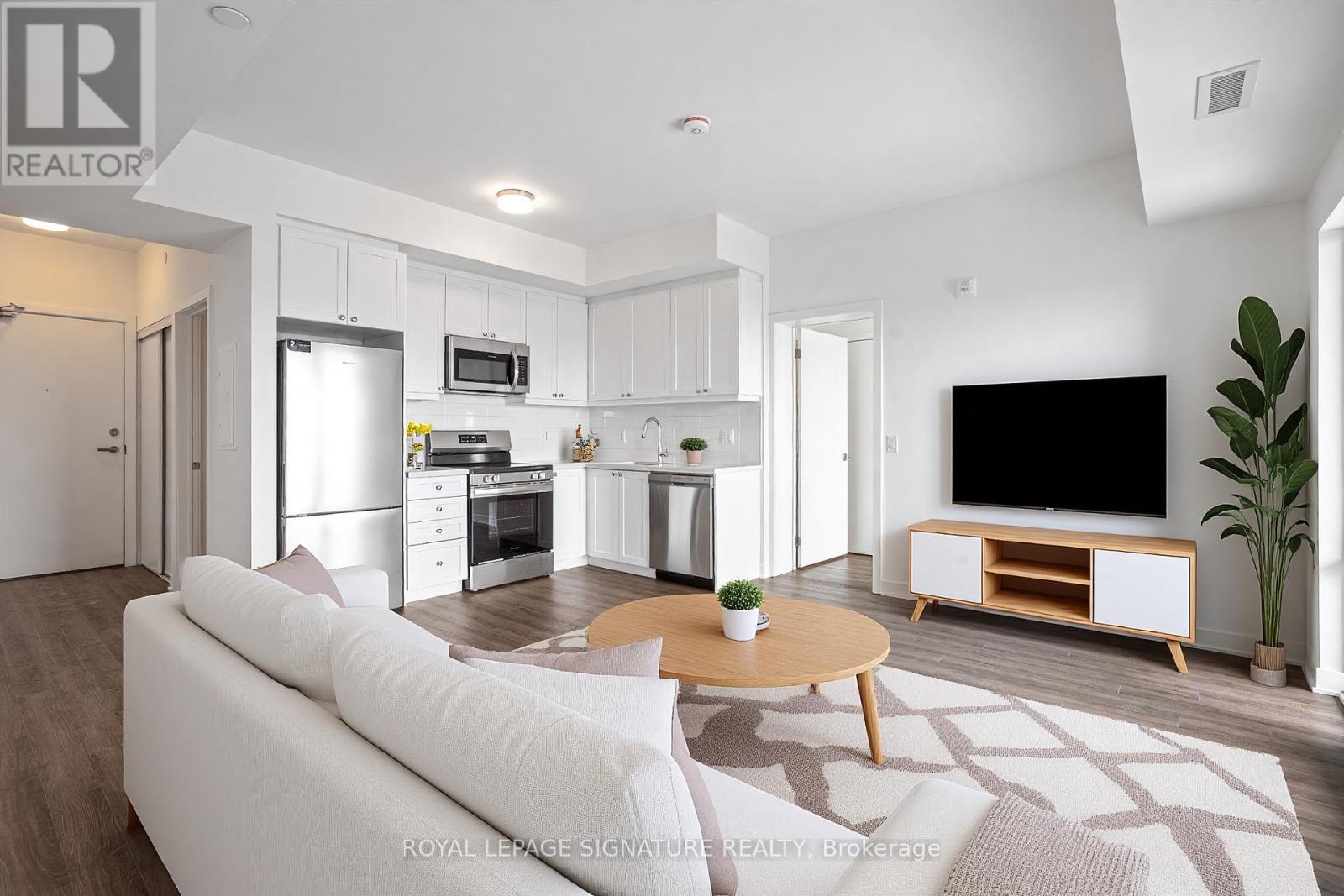 A modern living room with a white sofa, wooden coffee table, and a flat-screen TV.