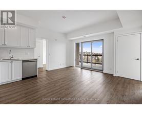 A spacious room with wooden flooring and a large window overlooking a body of water.