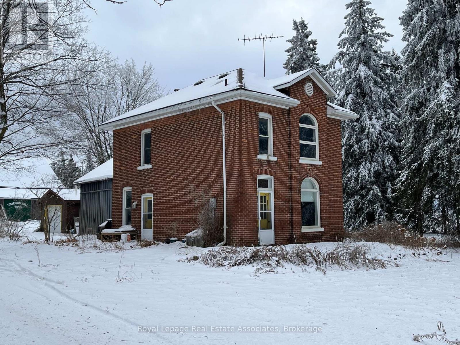 A red brick house with a snow covered roof and white trim.