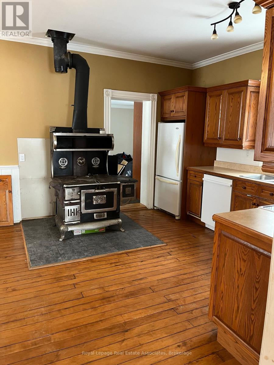 A wood burning stove in a kitchen with a white fridge.