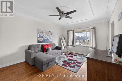 A living room with a grey couch and a ceiling fan.