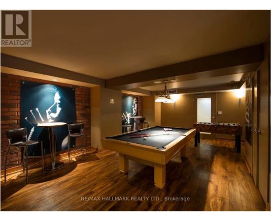 A pool table is in the middle of a room with a bar and a television.