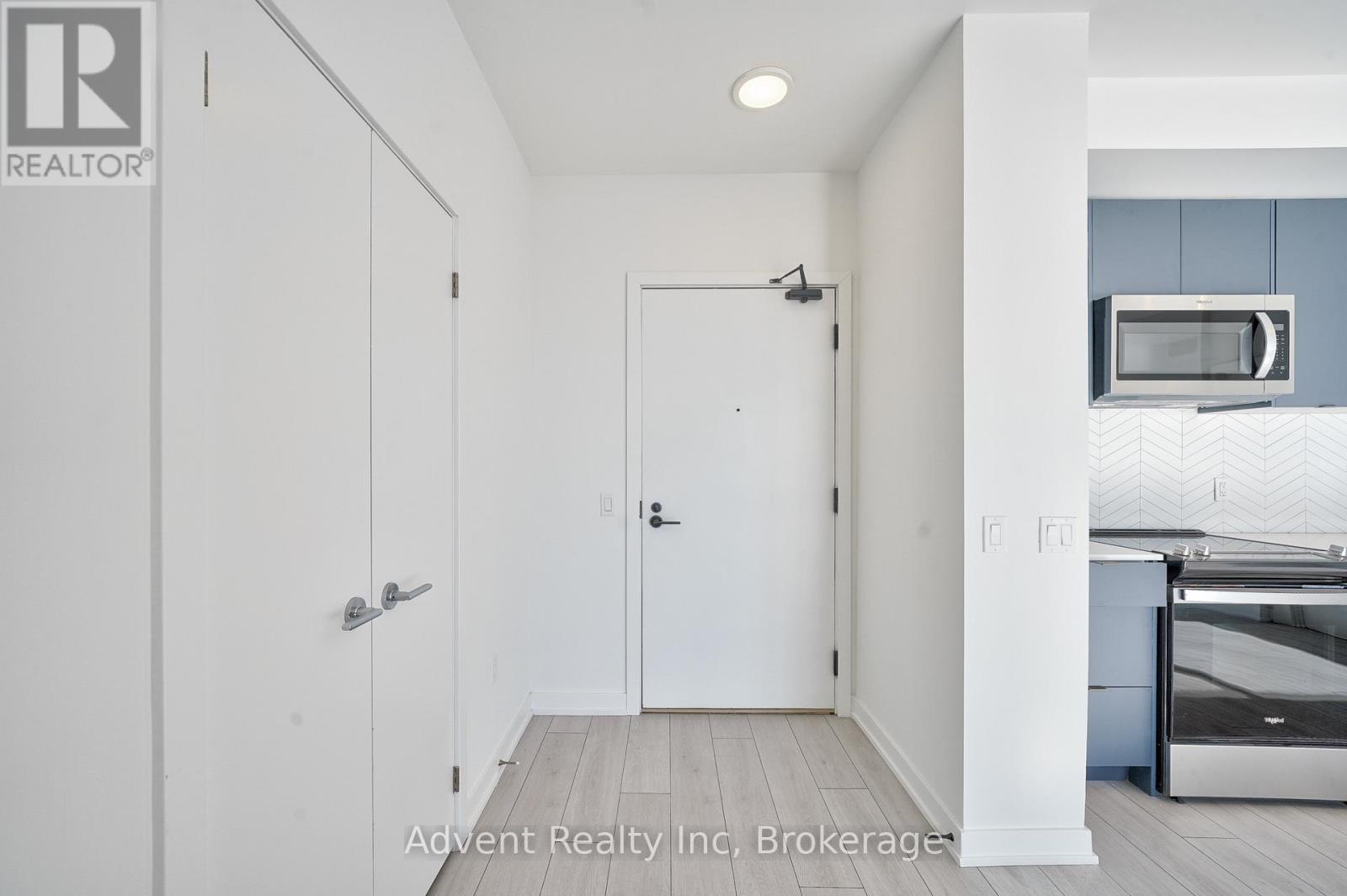 A white door with a silver handle is in a room with a white ceiling and a white floor.