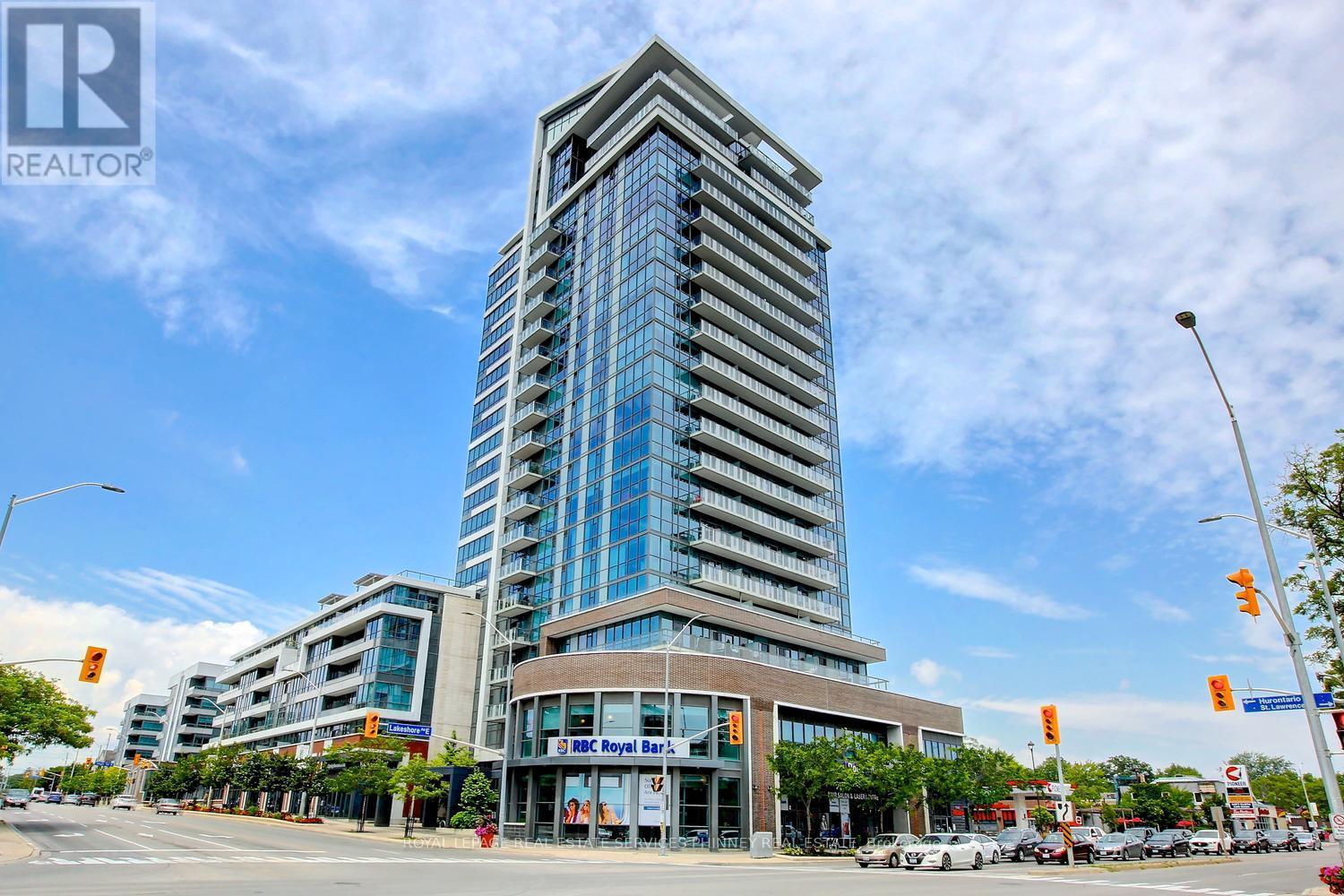 A tall building with a glass facade stands in front of a street with cars and traffic lights.