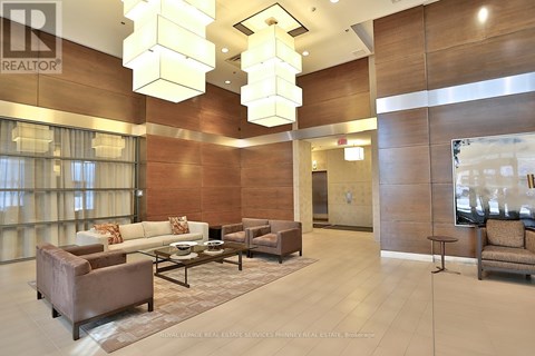 A well-lit, modern living room with a glass coffee table and a brown sofa.