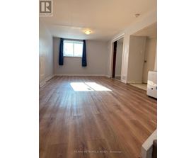 A room with wooden flooring and a window with blue curtains.