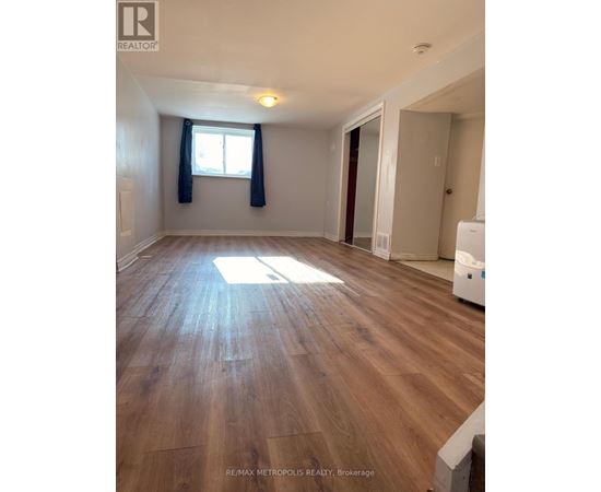 A room with wooden flooring and a window with blue curtains.