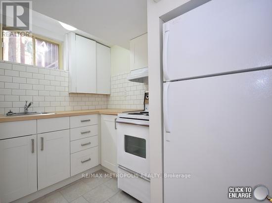 A white kitchen with a refrigerator on the right.