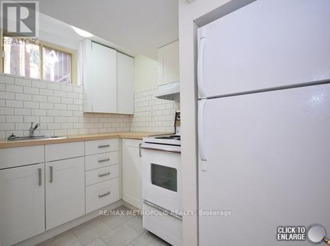 A white kitchen with a refrigerator on the right.