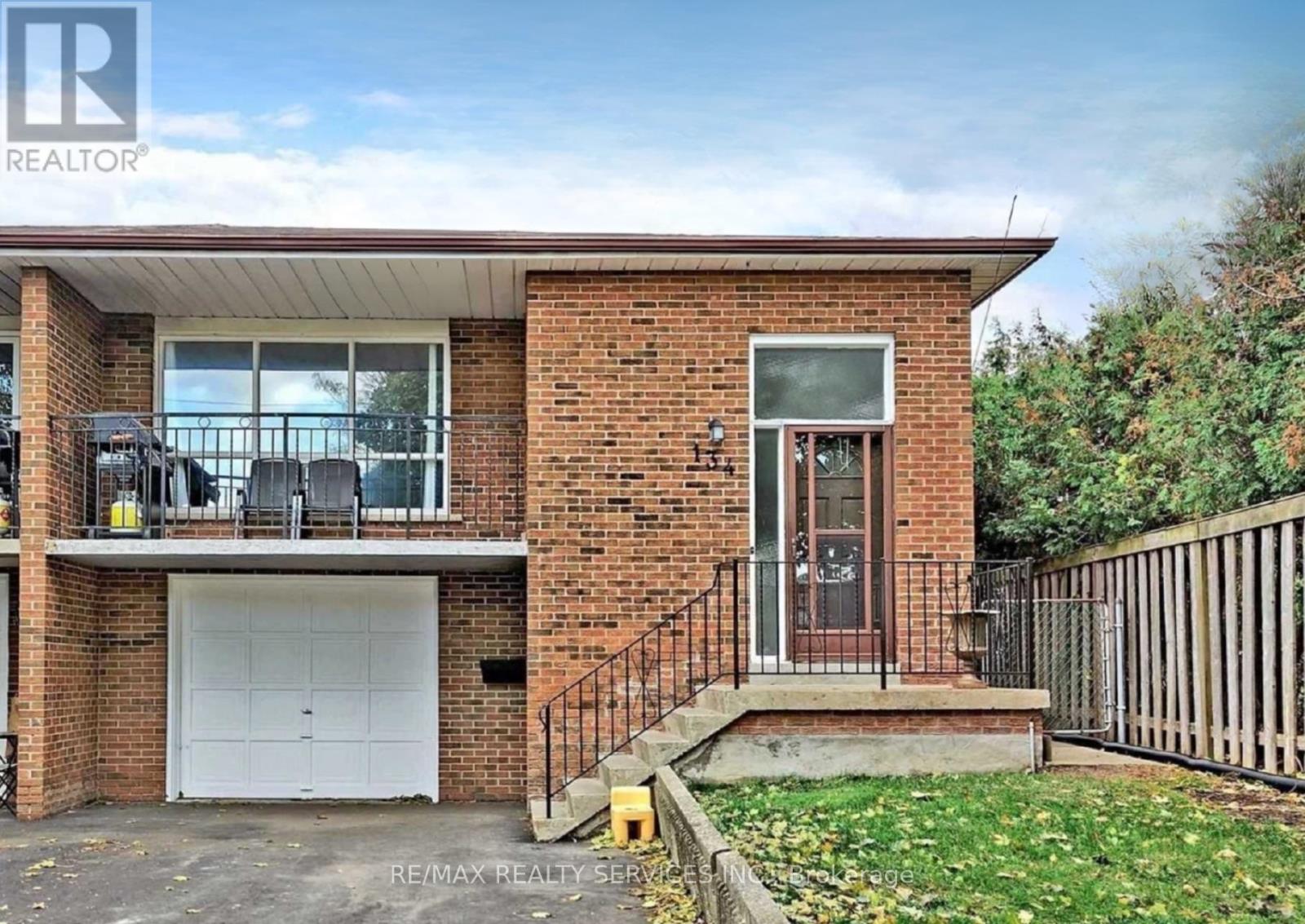 A two-story brick house with a garage and a balcony on the second floor.
