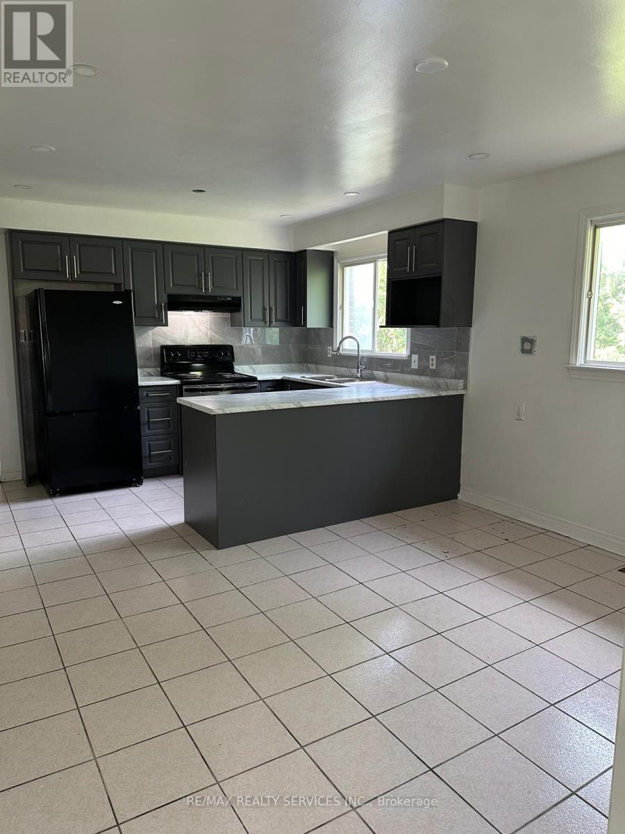 A kitchen with black cabinets and a black fridge.