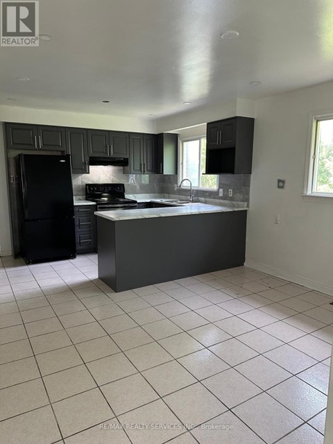 A kitchen with black cabinets and a black fridge.