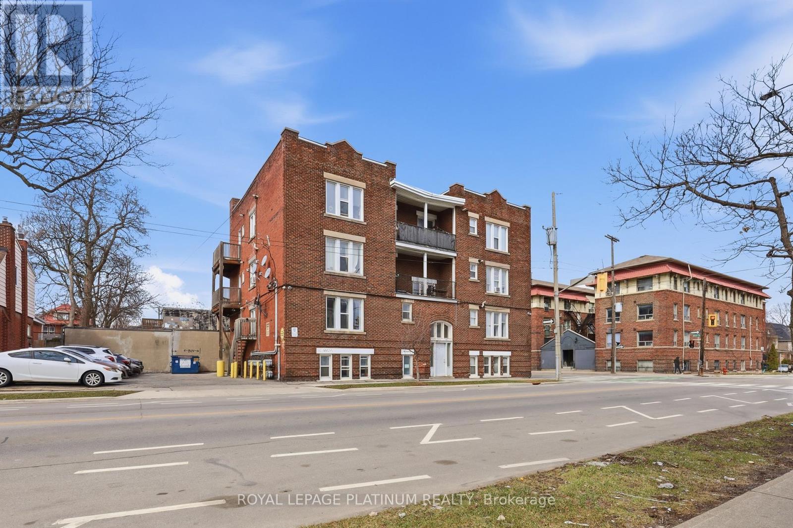 A street view of a multi-story brick building with a car parked in front.