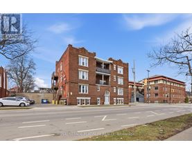 A street view of a multi-story brick building with a car parked in front.